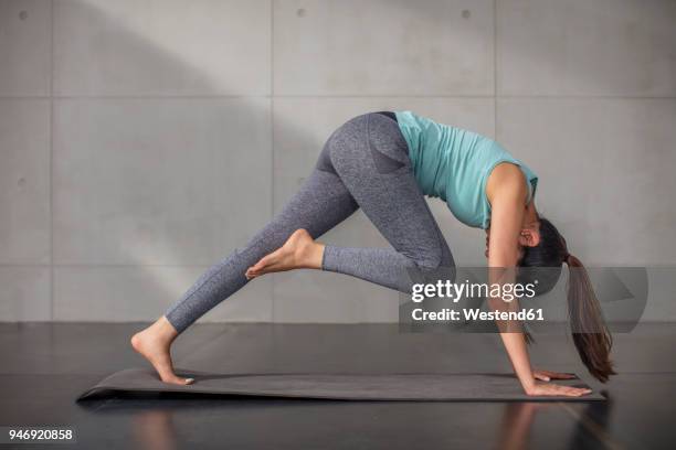 young woman doing yoga exercise in studio - buigen lichaamsbeweging stockfoto's en -beelden