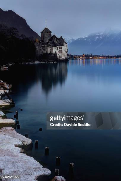 view of the chillon castle on the shore of the lake of geneva in the evening - chillon stock pictures, royalty-free photos & images