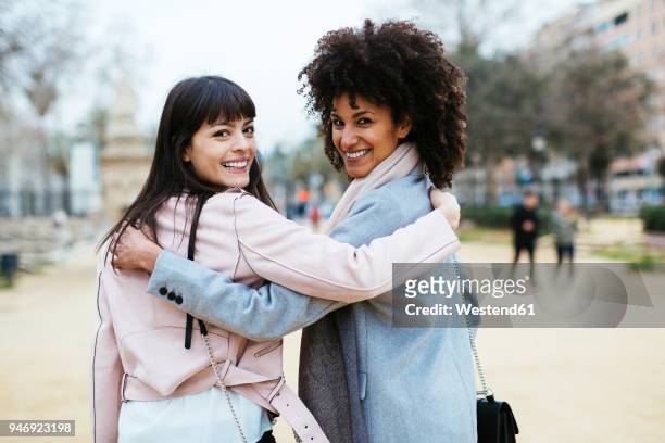 spain, barcelona, portrait of two happy women in city park embracing turning round - round two bildbanksfoton och bilder
