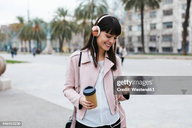 spain, barcelona, smiling woman with coffee, cell phone and headphones in the city - one young woman only photos et images de collection