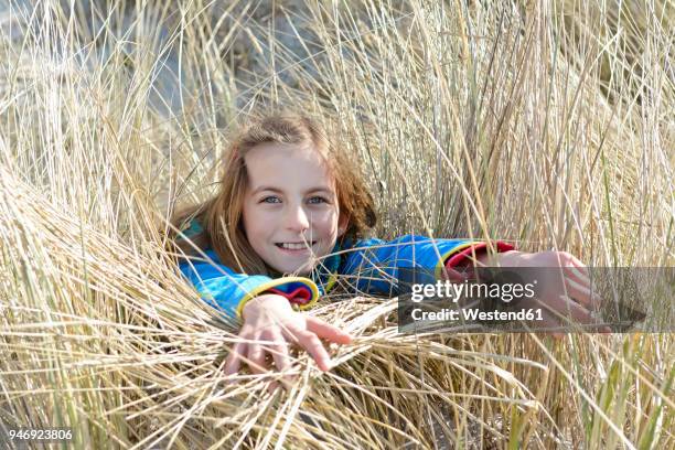 germany, hiddensee, portrait of smiling girl lying in grass of dunes - hiddensee stock-fotos und bilder
