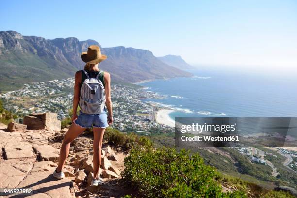 south africa, cape town, woman standing looking at the coast during hiking trip to lion's head - cidade do cabo - fotografias e filmes do acervo