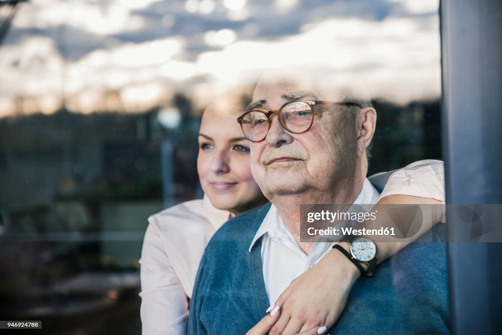 Portrait of young woman embracing senior man at the window