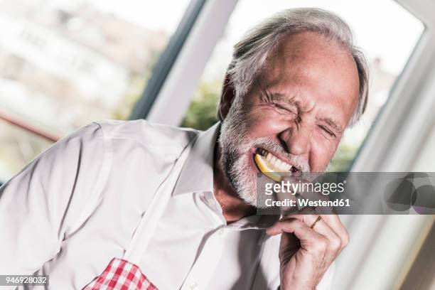 portrait of man eating lemon slice - küche probieren stock-fotos und bilder