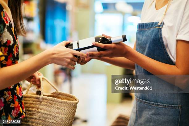 shop assistant handing over wine bottle to customer in a store - vinger bildbanksfoton och bilder