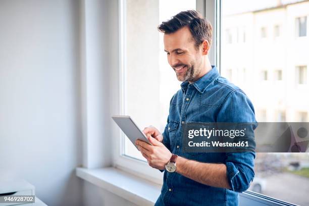 smiling man using tablet at the window - casual businessman stockfoto's en -beelden