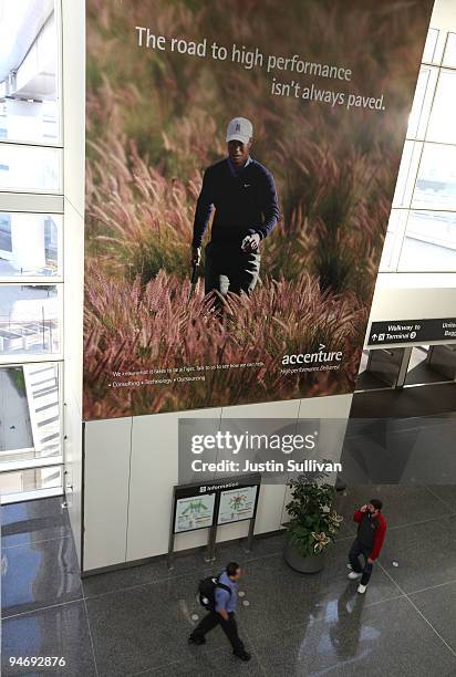 Travelers walk by an advertisement for Accenture that features professional golfer Tiger Woods December 17, 2009 at San Francisco International...