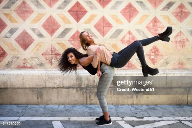 laughing woman carrying her best friend piggyback - piernas en el aire fotografías e imágenes de stock