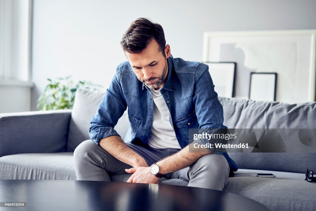 Worried sad man sitting on sofa