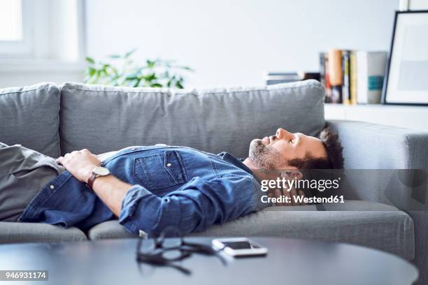 relaxed man sleeping on sofa - supino foto e immagini stock