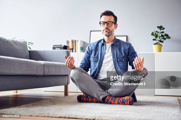 relaxed man meditating at home - meditar fotografías e imágenes de stock