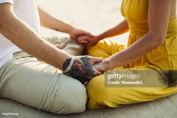 close-up of tattooed man holding hands of woman - couple doing yoga stock pictures, royalty-free photos & images