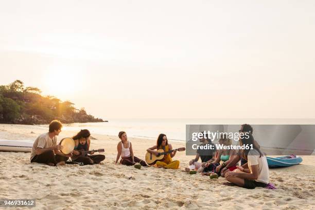 thailand, koh phangan, group of people sitting on a beach with guitar at sunset - coconut beach woman stock pictures, royalty-free photos & images