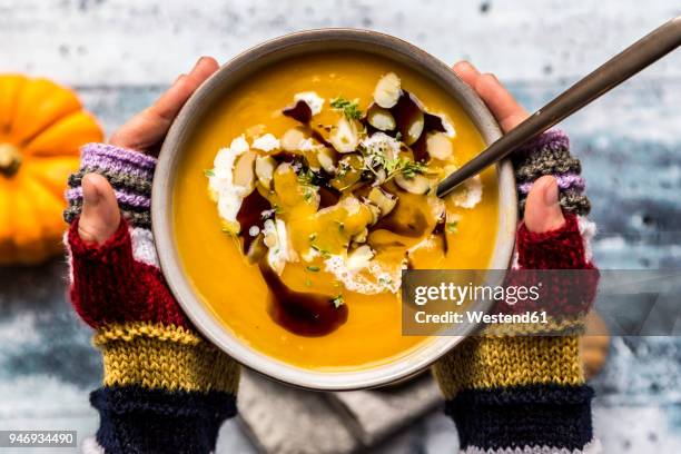 girl's hands holding bowl of creamed pumpkin soup - kürbissuppe stock-fotos und bilder