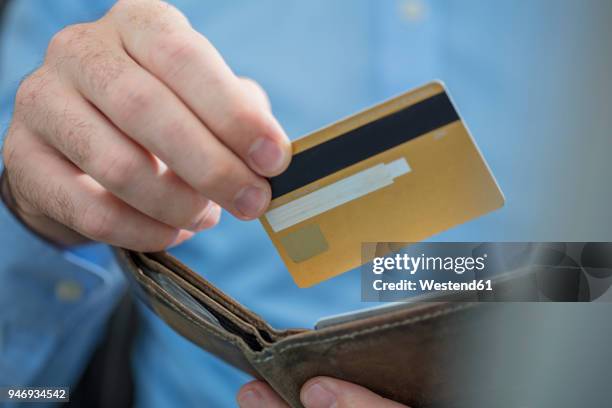 man's hands holding credit card and purse, close-up - gold purse stock-fotos und bilder