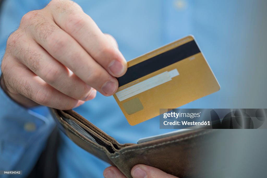 Man's hands holding credit card and purse, close-up