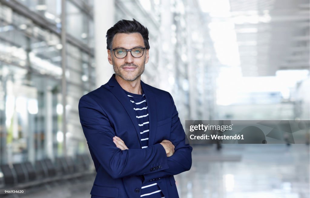 Portrait of stylish businessman with stubble wearing blue suit and glasses