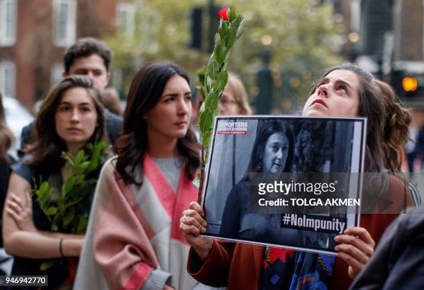 Demonstrators hold posters depicting murdered Maltese journalist Daphne Caruana Galizia as they attend a protest vigil outside the Maltese High...