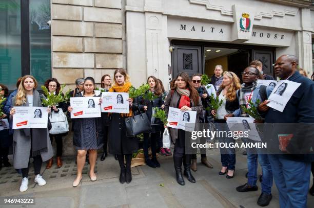 Demonstrators hold posters depicting murdered Maltese journalist Daphne Caruana Galizia as they attend a protest vigil outside the Maltese High...