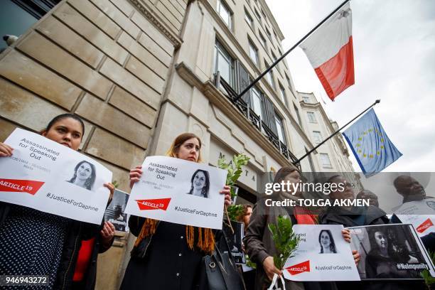 Demonstrators hold posters depicting murdered Maltese journalist Daphne Caruana Galizia as they attend a protest vigil outside the Maltese High...