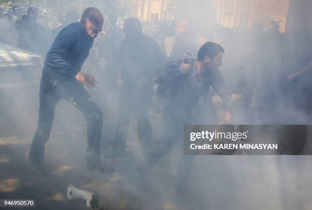 Armenian opposition supporters scatter during clashes with police at a rally in central Yerevan on April 16, 2018. Around a thousand protesters...