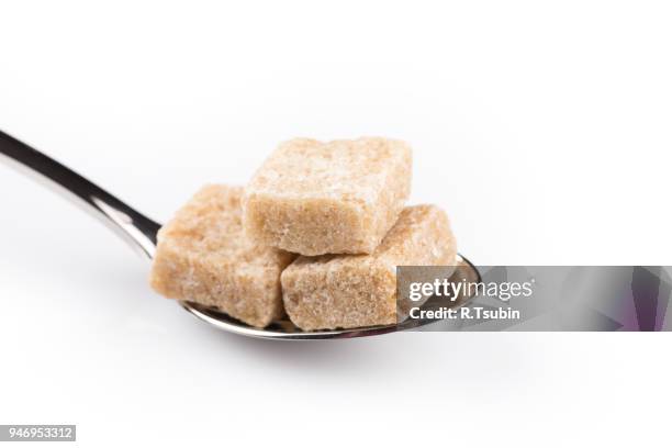 cubes of brown sugar on a metal spoon isolated - panela stock pictures, royalty-free photos & images