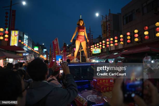 Pole dancers perform on the roofs of cars as they take part in a parade near Xingang Fengtian Temple where the statue of Mazu will rest for two...
