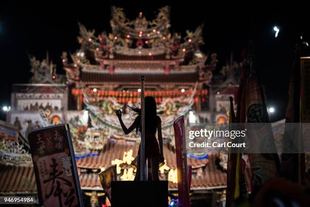 Pole dancer performs on the roof of a car in front of Xingang Fengtian Temple where the statue of Mazu will rest for two nights before resuming its...