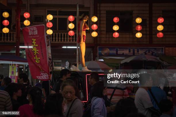 Pole dancer pauses between performances on the roof of a car during a parade near Xingang Fengtian Temple where the statue of Mazu will rest for two...