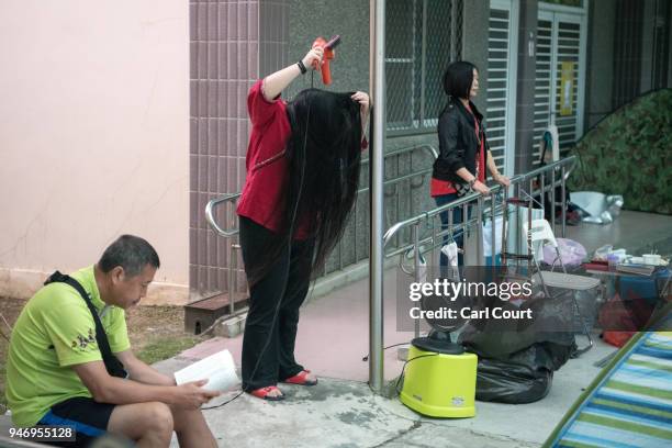 Woman dries her hair as she camps in a school near Xingang Fengtian Temple that has been allocated for pilgrims who are following the statue of Mazu...