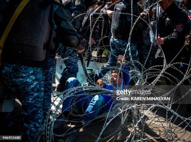 An armenian opposition supporter falls on barbed wire during a dispersal of a rally in central Yerevan on April 16, 2018. An opposition leader and...