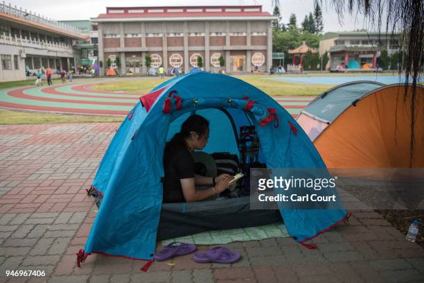 Woman checks her phone in her tent pitched in a school near Xingang Fengtian Temple that has been allocated for pilgrims who are following the statue...