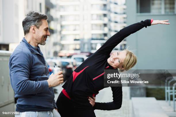 portrait of a content mature woman and a man stretching after a run in the city - mature couple winter outdoors stockfoto's en -beelden