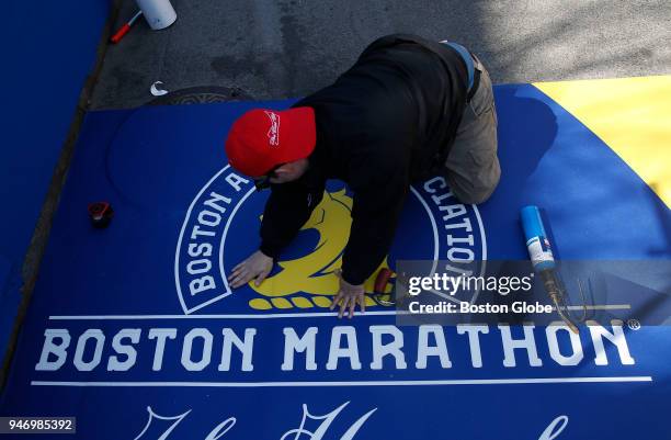 Jonathan Rodriguez, of Peabody, works to place the finish line for the 2018 Boston Marathon on Boylston Street in Boston on April 12, 2018.