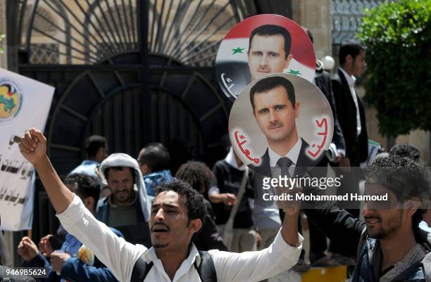 Yemeni men hold photos of Syrian President Bashar al-Assad during a protest against U.S. Allied missile strikes against Syria outside the Syrian...