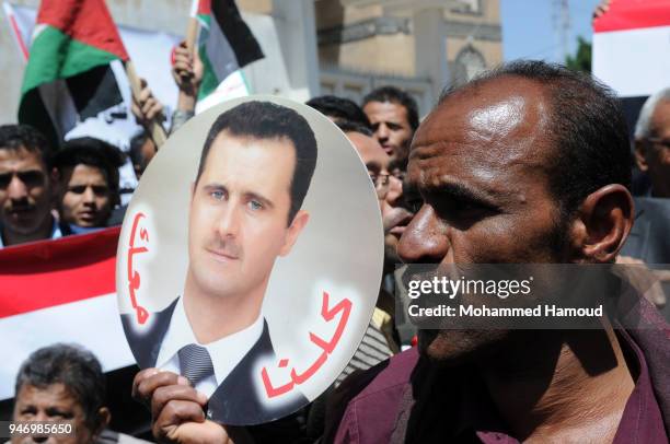 Yemeni man holds a photo of Syrian President Bashar al-Assad during a protest against U.S. Allied missile strikes against Syria outside the Syrian...