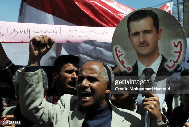 Yemeni man holds a photo of Syrian President Bashar al-Assad during a protest against U.S. Allied missile strikes against Syria outside the Syrian...