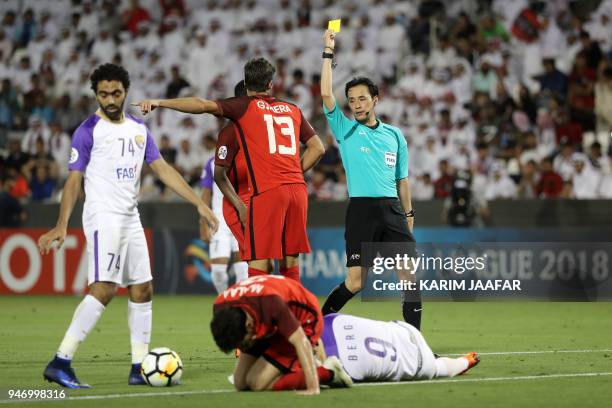 Japanese referee Hiroyuki Kimura issues a yellow card to Al-Rayyan SC's Uruguayan defender Gonzalo Viera during the Asian Champions League football...