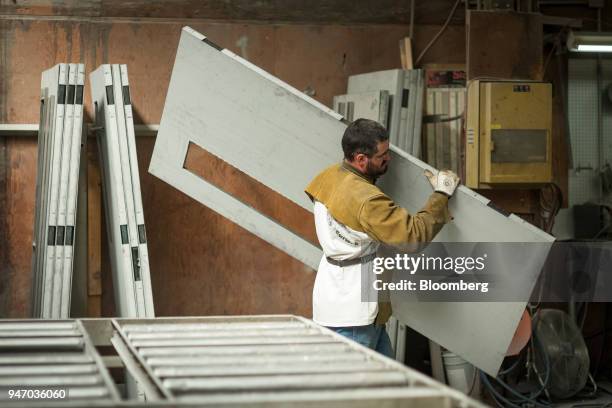 Worker carries a metal door during production at the Metal Manufacturing Co. Facility in Sacramento, California, U.S., on Thursday, April 12, 2018....