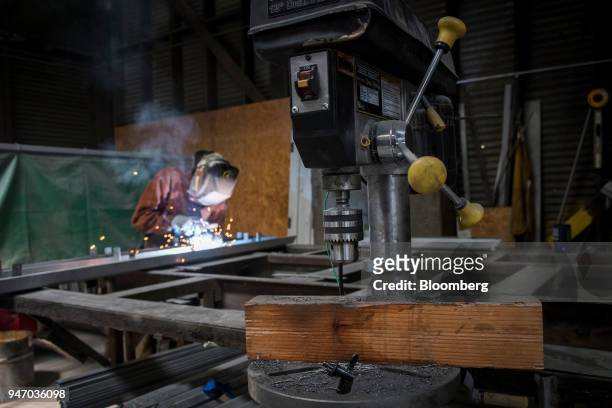 Drill press sits as a worker arc welds at the Metal Manufacturing Co. Facility in Sacramento, California, U.S., on Thursday, April 12, 2018. The...