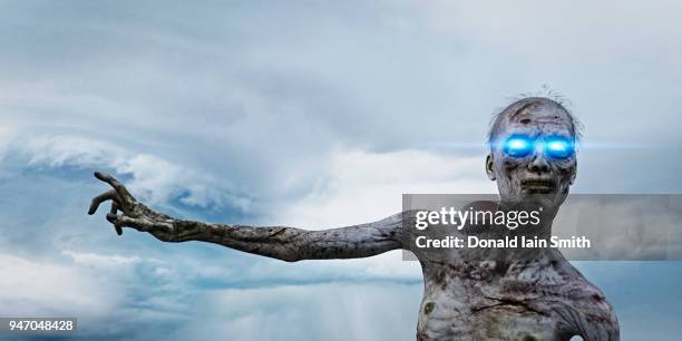 zombie with brightly glowing blue eyes reaching out with hand - zombie hand stock pictures, royalty-free photos & images