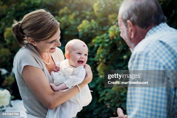 mother holding baby with traditionnal baptism robe. - baptism stock pictures, royalty-free photos & images