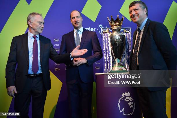 Prince William, Duke of Cambridge poses next to the English Premier League football trophy during a 'Welcome to the UK' reception on the opening day...