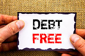 Writing text showing  Debt Free. Concept meaning Credit Money Financial Sign Freedom From Loan Mortage written on Sticky Note Paper Holding Hand with Finger.