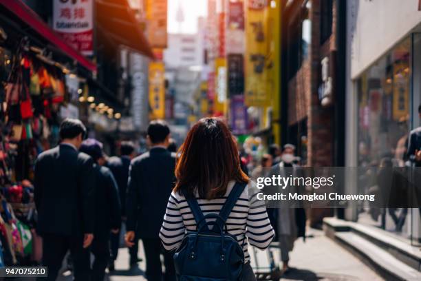 young asian woman traveler traveling and shopping in myeongdong street market at seoul, south korea. myeong dong district is the most popular shopping market at seoul city. - korea stock-fotos und bilder