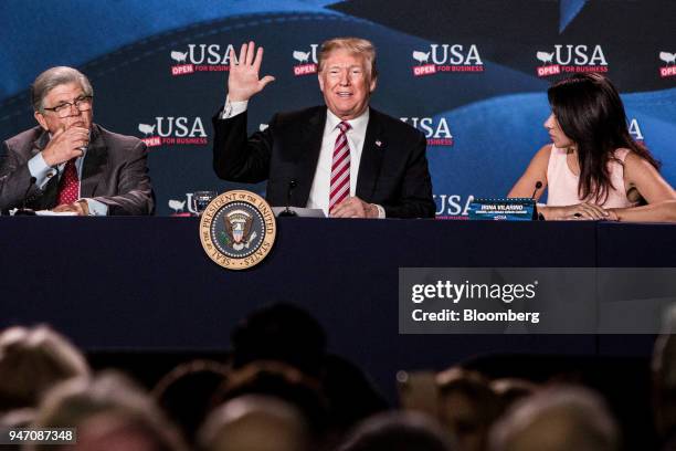 President Donald Trump, center, waves while sitting next to Maximo Alvarez, president of Sunshine Gasoline Distributors, left, and Irina Vilarino,...