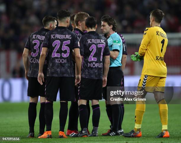Referee Guido Winkmann explains to the players of Freiburg his decision to recall the teams and award a penalty before half time during the...
