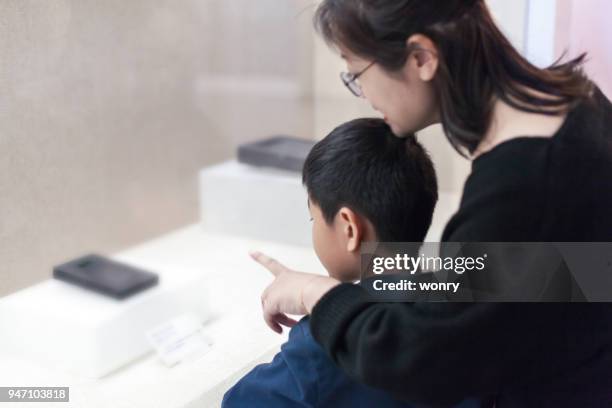 mother and son watching crafts indoors - family museum stock pictures, royalty-free photos & images