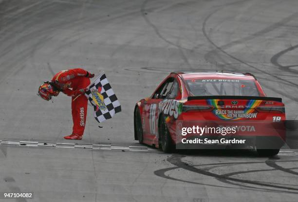 Kyle Busch, driver of the Skittles Toyota, celebrates with the checkered flag after winning the rain delayed Monster Energy NASCAR Cup Series Food...