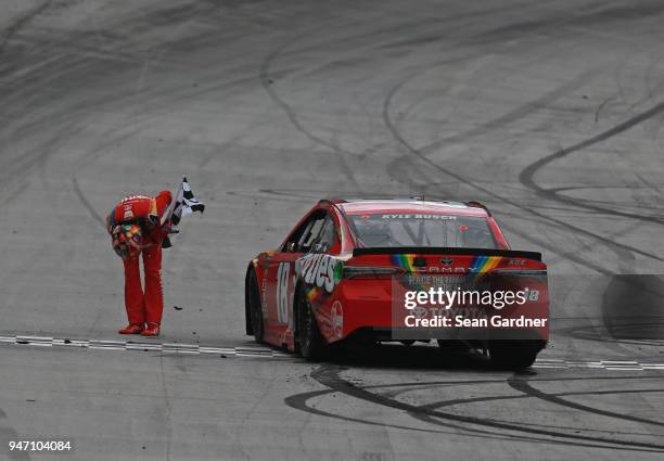 Kyle Busch, driver of the Skittles Toyota, celebrates with the checkered flag after winning the rain delayed Monster Energy NASCAR Cup Series Food...